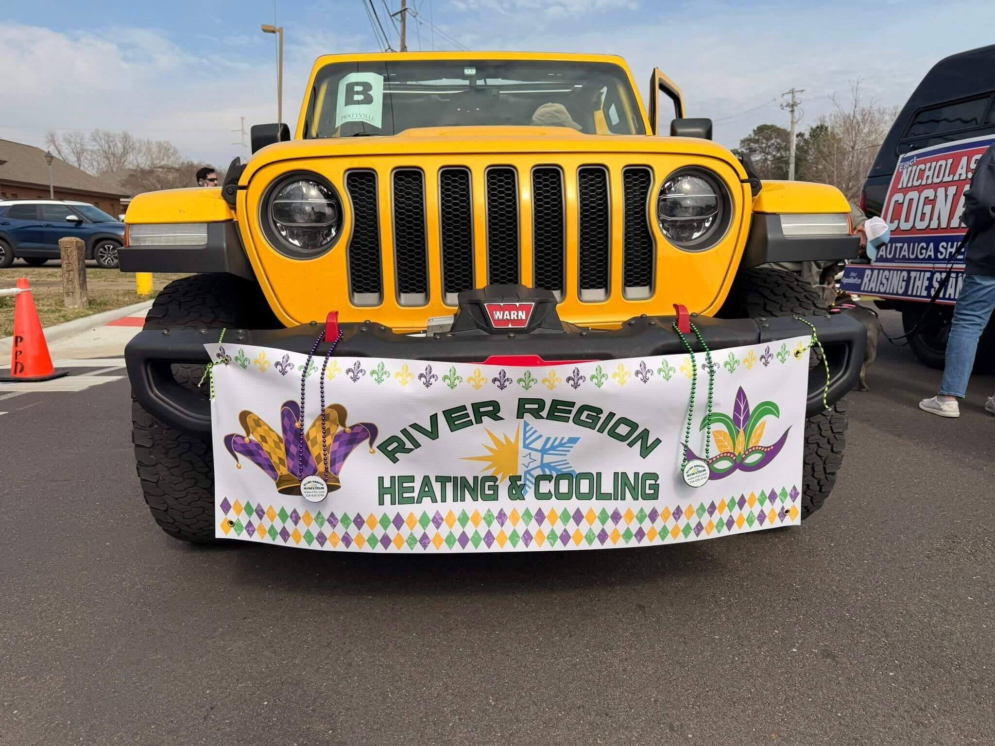 A yellow truck in Millbrook with a Mardi Gras banner for River Region